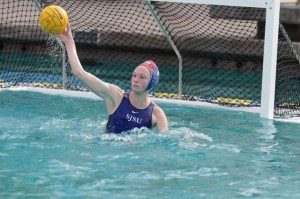 Female water polo player in the water hitting ball.