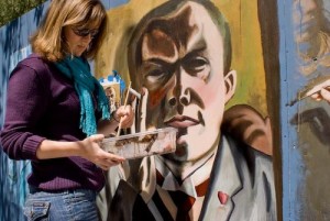 Female student (Kelsey) with paint brush working on mural of Max Beckmann.