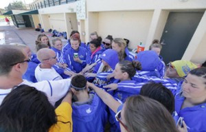 The swim team gathers for a group huddle. 