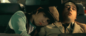 A young man wearing a hat rests his head on another young man's shoulder, while they sit in a car. Image from Cinequest film “Cheap Fun.” Photo courtesy of Cinequest.