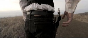 Backside view of cowboy grabbing gun