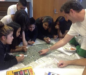 Using a map of the neighborhood, profesor Rick Kos leads youth through an exercise that helps them identify neighborhood assets and constraints. Photo by Dayana Salazar