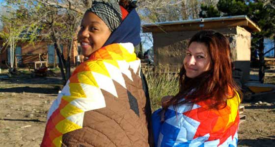 Two female students covered in colorful Navajo blankets.