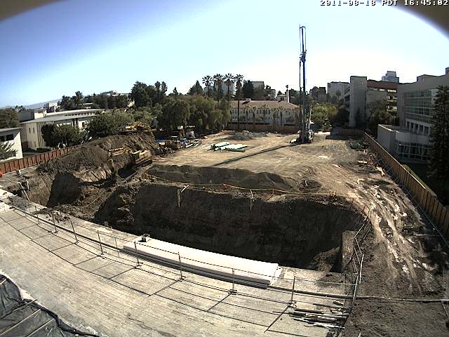 Aerial view of construction at the west side of the Student Union, including a tall pile driver and a big hole in the ground. Photo courtesy of MoreCampusLife.com