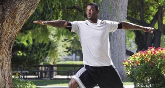 James Jones in yoga pose outdoors on campus.