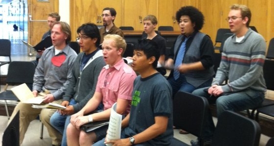 two rows of male singers in a practice room