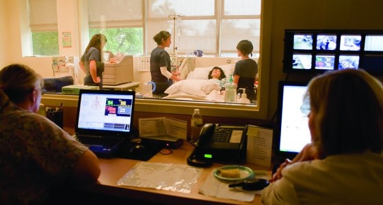 Nursing faculty members observe students working in the nursing sim lab.