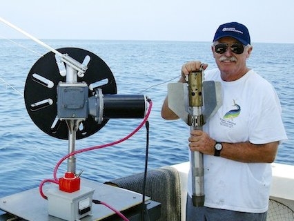 scientist at sea with a "corer" used to drill down into the ocean floor