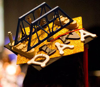 Close up of 3D bridge and small monuments with the name "Diana" on a woman's graduation cap. Photo by Christina Olivas.