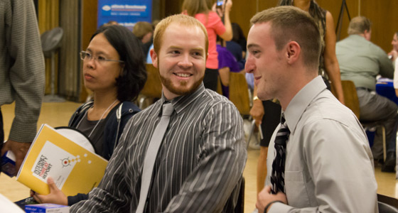Two young men wearing ties and collared shirtschat during the Cyber Challenge job fair.