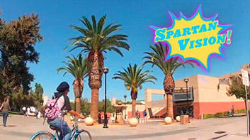 Cyclist biking near Event Center at SJSU with the graphic "Spartan Vision!" on it