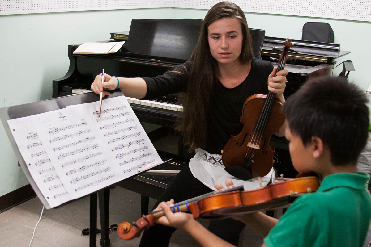 SJSU student gives a one-on-one violin lesson to a boy.