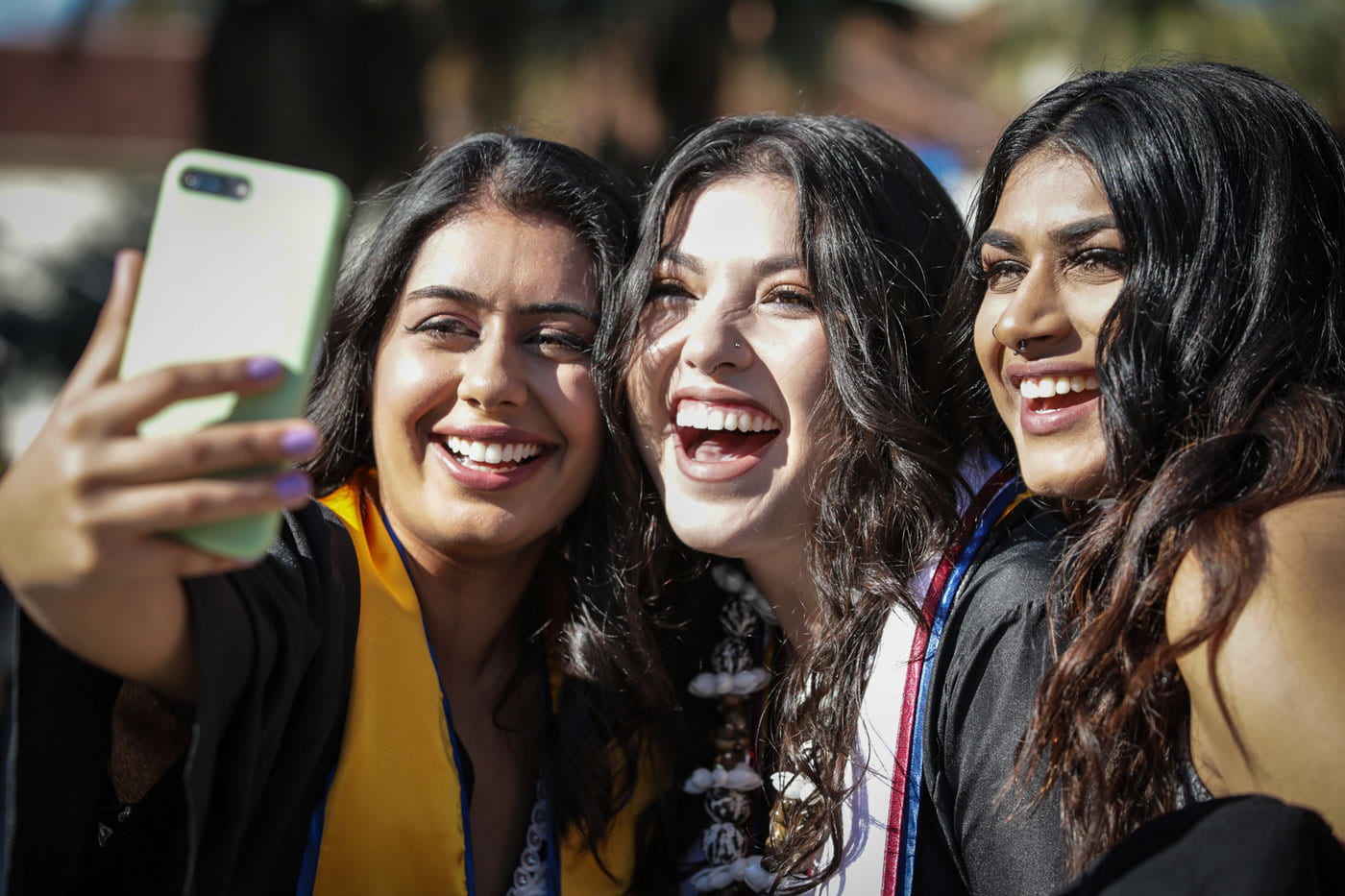 SJSU graduates smile while taking a selfie.