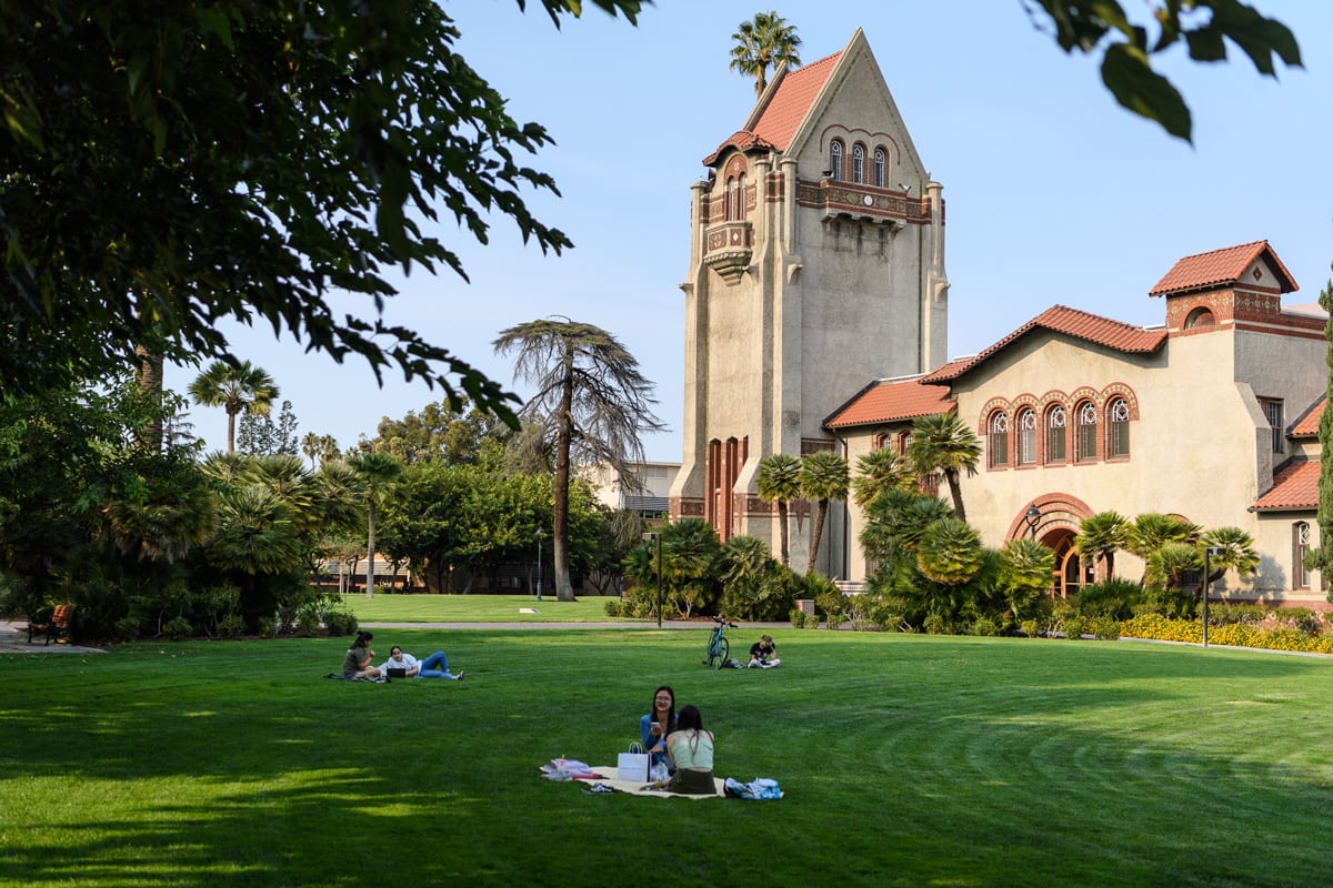 Tower hall on a sunny day with students laying on the grass.