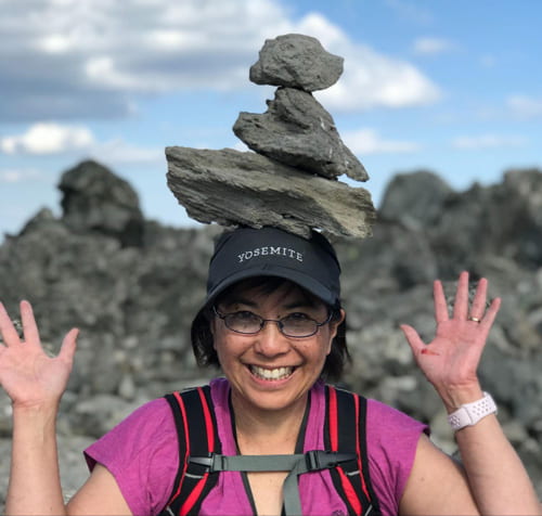 LeAnne Teruya balancing stacked rocks on her head.