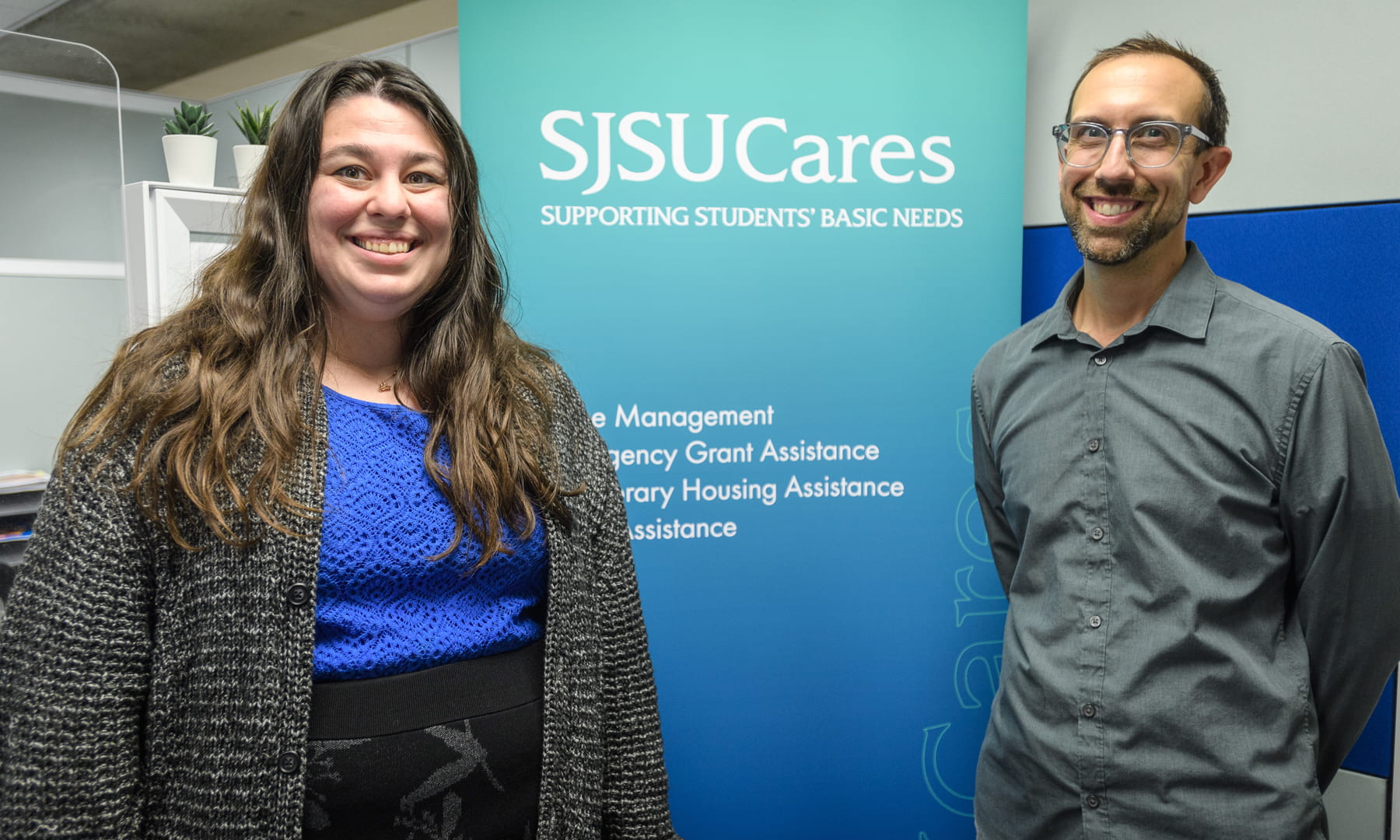 Two people in front of a sign that says SJSU Cares