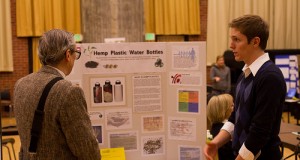 Junior JD Leadam stands to the left of his project poster board for Hemp Plastic Water Bottles presented his idea to a passerby. Poster board includes a picture of the design and an explanation of his project